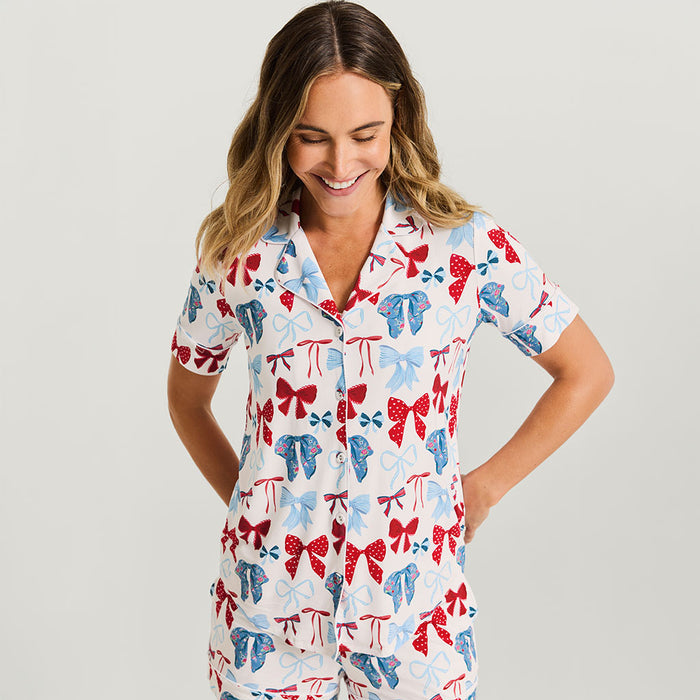 Woman wearing a colorful bow-patterned pajama set on a plain background