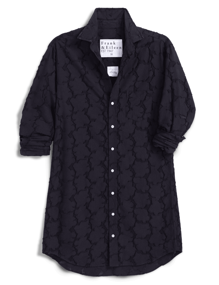 A black dress by Frank & Eileen, featuring a textured, embossed trellis pattern. The dress is shown with the sleeves rolled up, set against a solid dark green background.