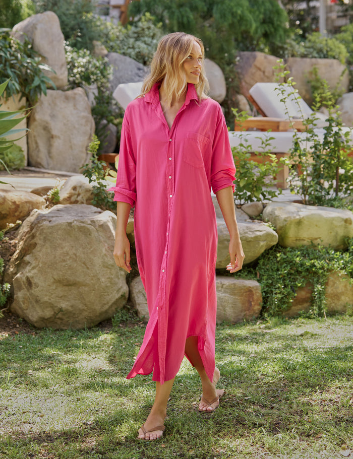 Woman wearing a pink dress standing in a garden with rocks and plants.