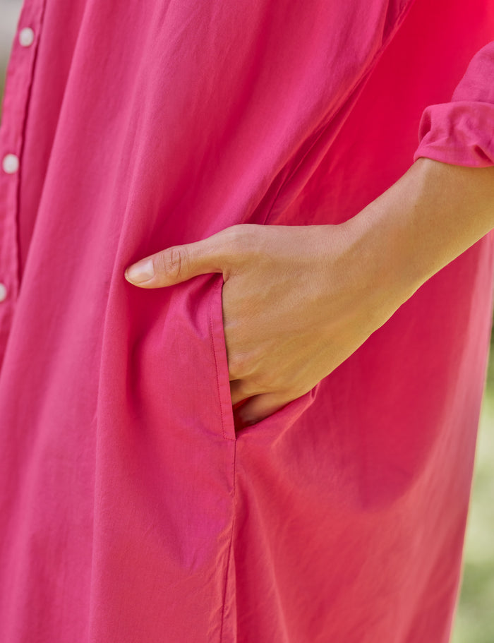 Person wearing a bright pink dress with a blurred background