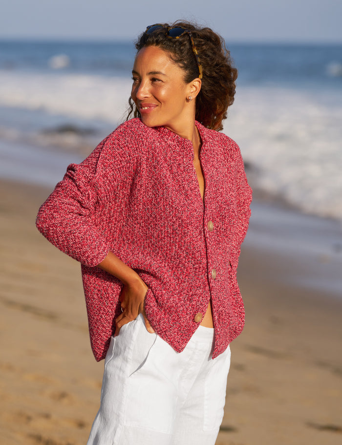 Woman wearing a red cardigan on a beach