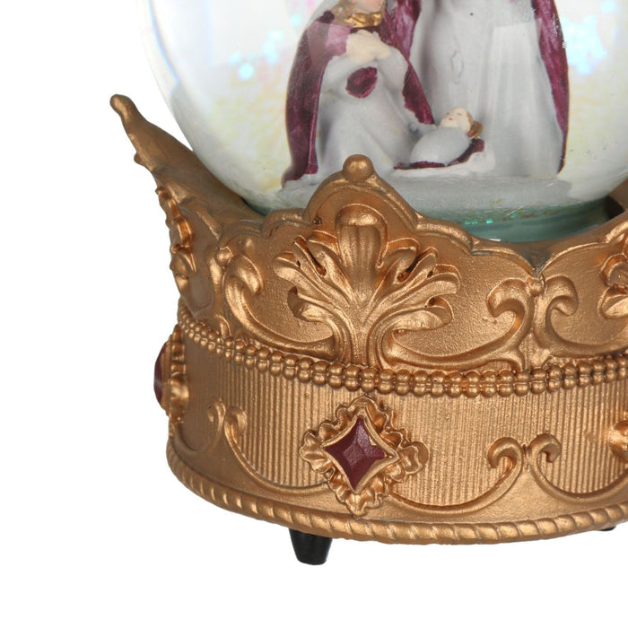 Decorative gold base with a glass sphere containing a nativity scene on a white background