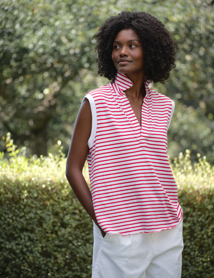 Woman wearing a red and white striped sleeveless top with a blurred green background