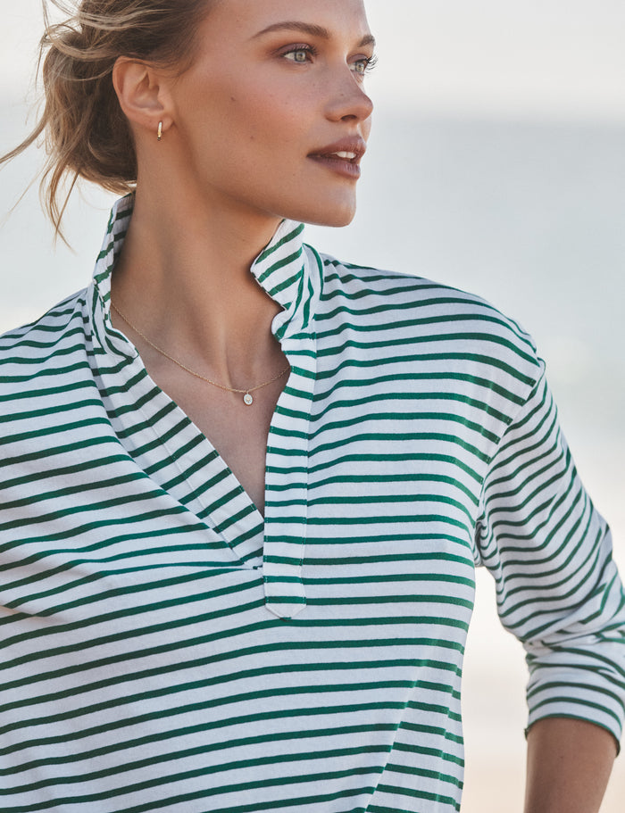 Woman wearing a green and white striped shirt against a blurred natural background
