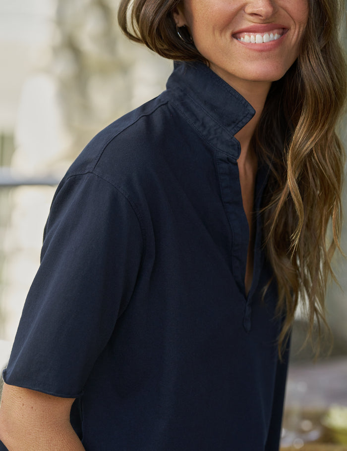 Woman wearing a navy blue shirt with a blurred background