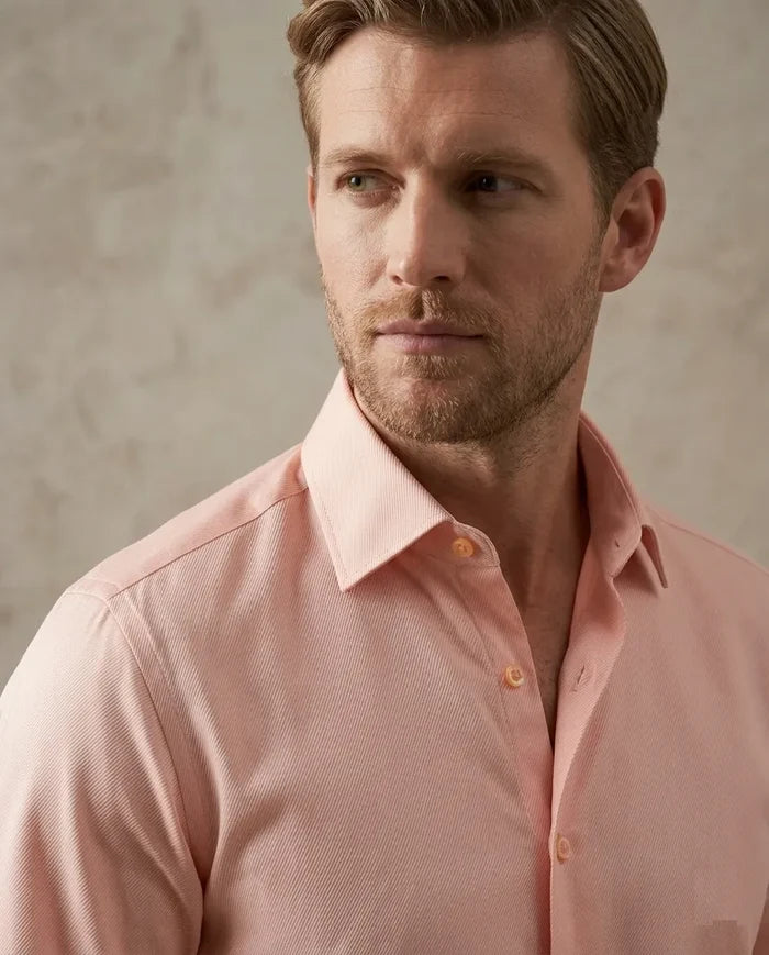 Man wearing a light pink dress shirt against a neutral background