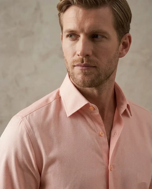 Man wearing a light pink dress shirt against a neutral background