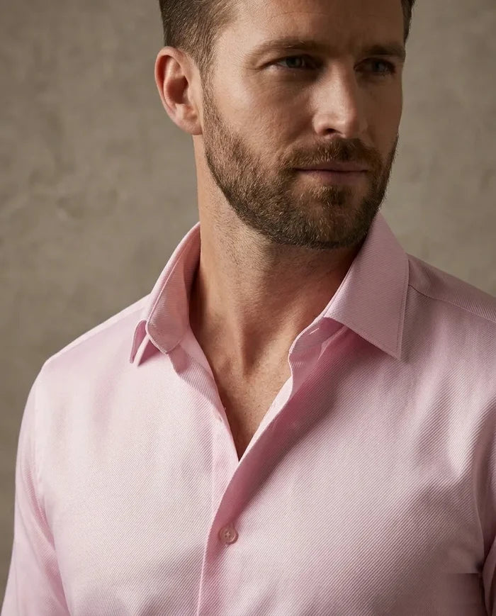 Man wearing a pink shirt against a neutral background