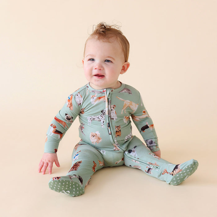 Baby wearing a green dog-patterned onesie on a beige background