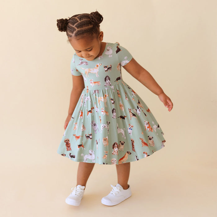 Child wearing a dress with dog pattern on a beige background