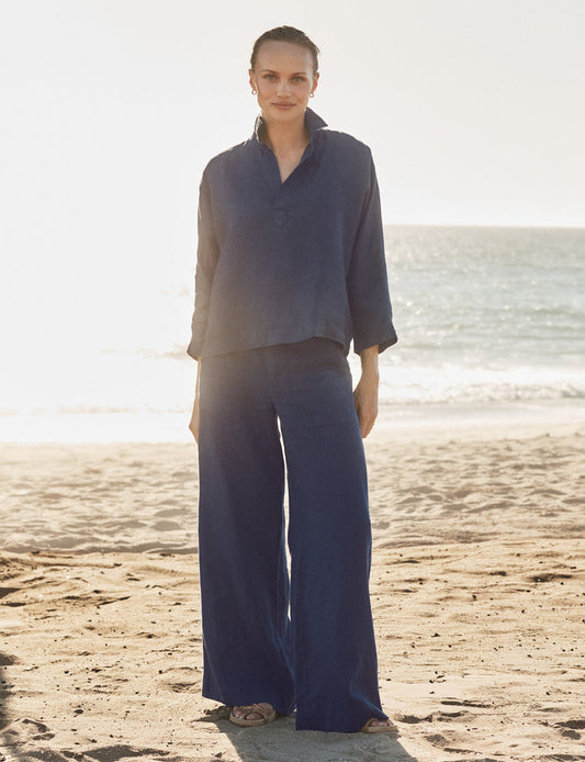 Woman in a blue outfit standing on a beach with ocean in the background