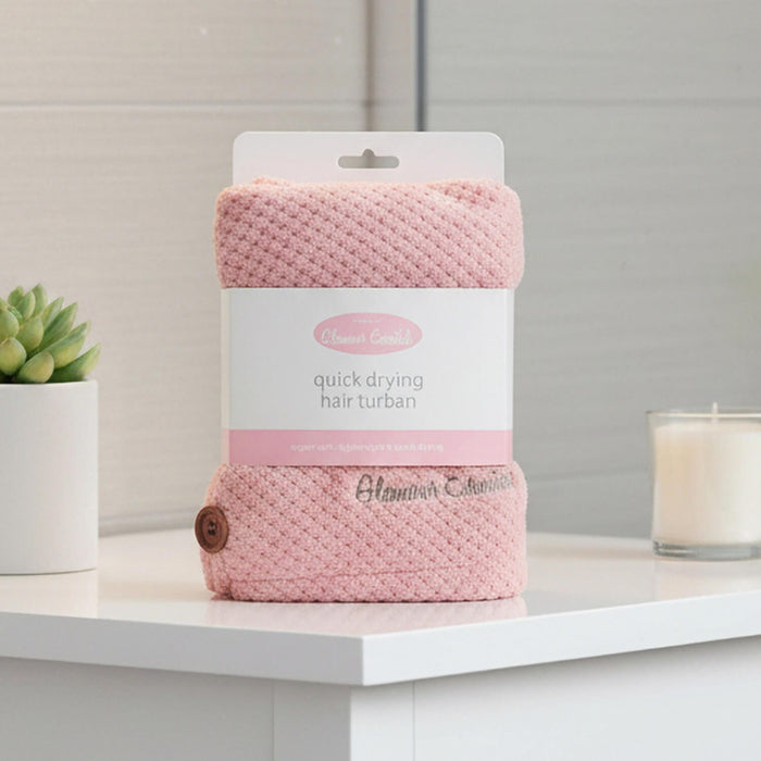 Pink quick drying hair turban in packaging on a shower room cabinet with candle and plant