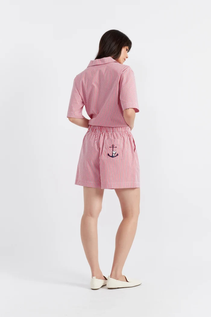 Woman wearing a pink outfit with an anchor design on a white background