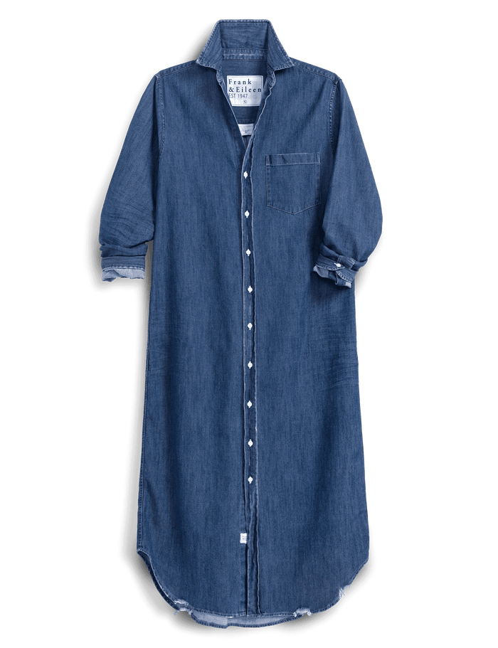 A blue denim shirt dress with a pointed collar, button-down front, and rolled cuffs, shown against a solid green background.