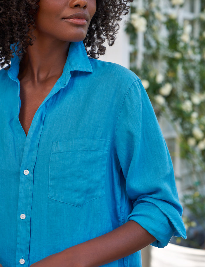 Person wearing a blue dress with a blurred outdoor background