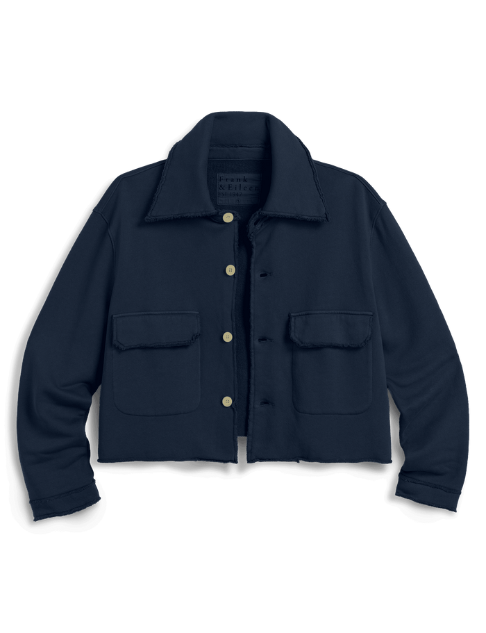 A dark navy blue cropped utility jacket with a pointed collar, button front, and two front flap pockets, shown against a solid green background.