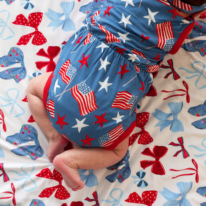 Baby in a blue diaper with American flag pattern on a colorful background