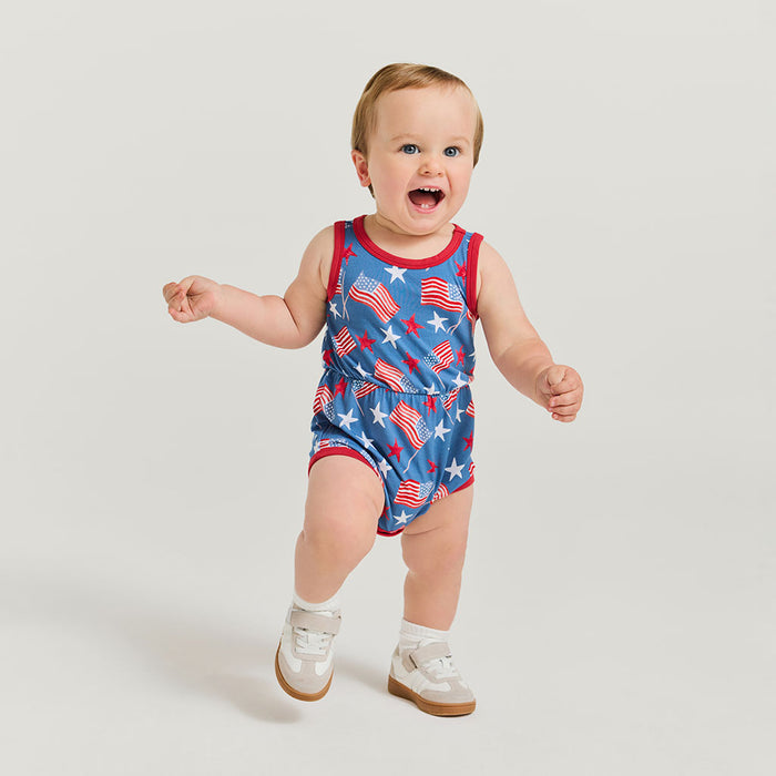 Baby wearing a red, white, and blue romper with flag pattern on a light gray background