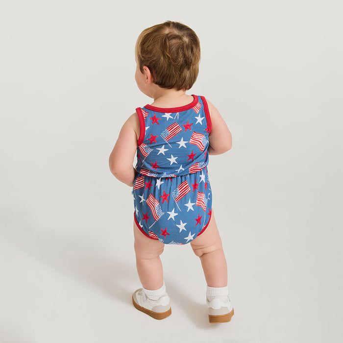 Baby wearing a red, white, and blue romper with star and stripe pattern on a light gray background
