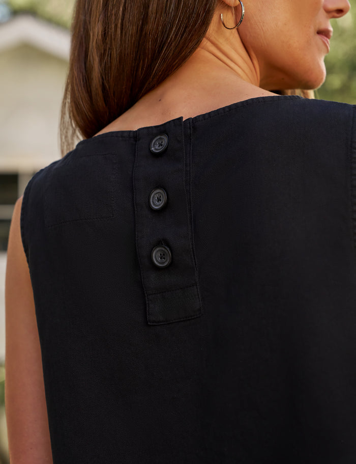Black sleeveless top with button details on a blurred background