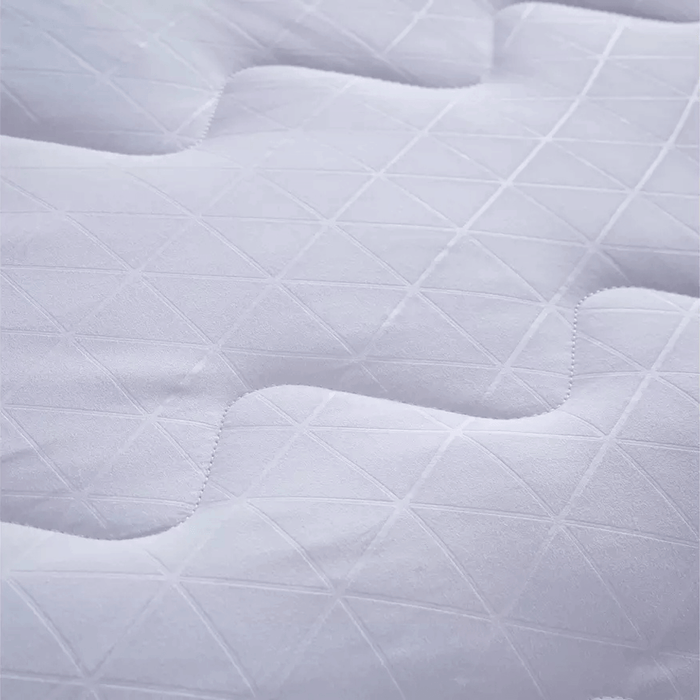 Close-up of a quilted white mattress pad with diamond pattern