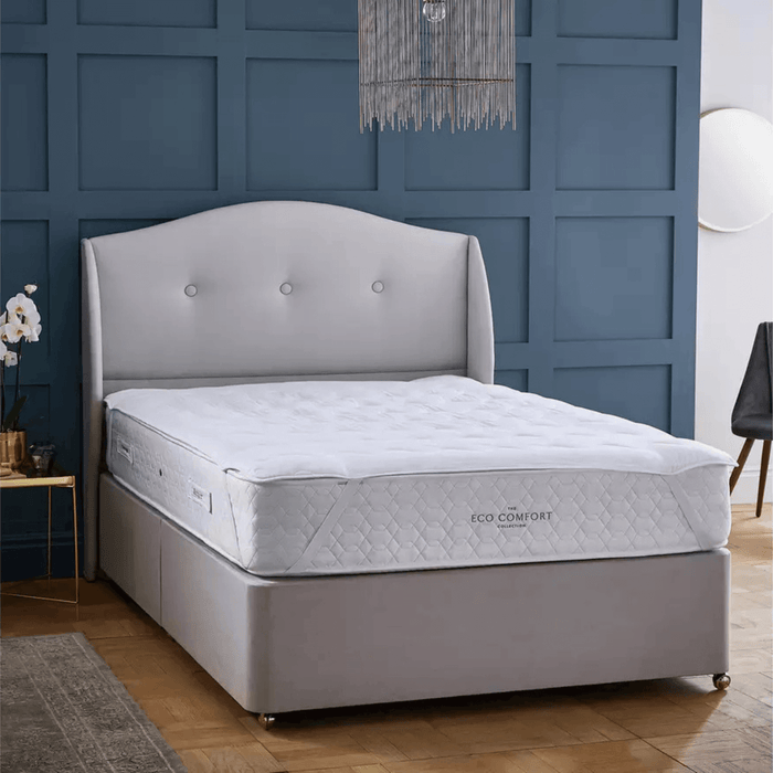 Gray bed with a mattress in a room with blue walls and wooden flooring.