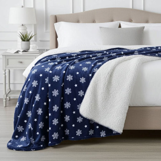 Blue blanket with white snowflake pattern draped over a bed in a bedroom setting.