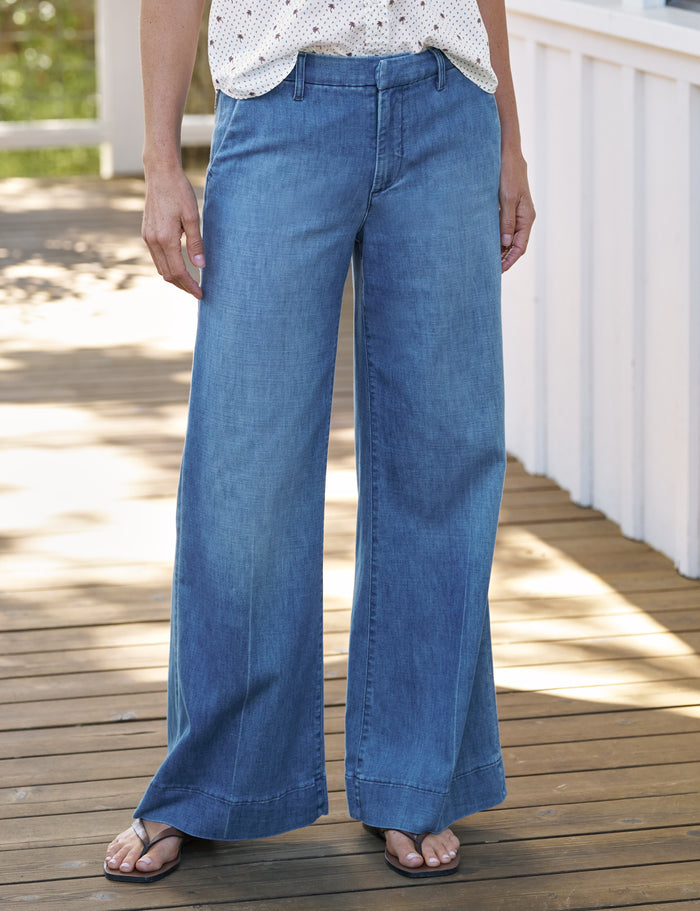 Person wearing blue wide-leg jeans on a wooden deck