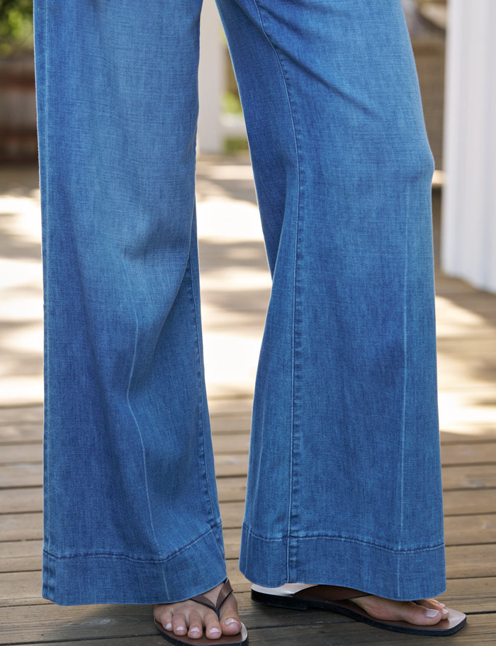 Blue jeans worn by a person on a wooden deck