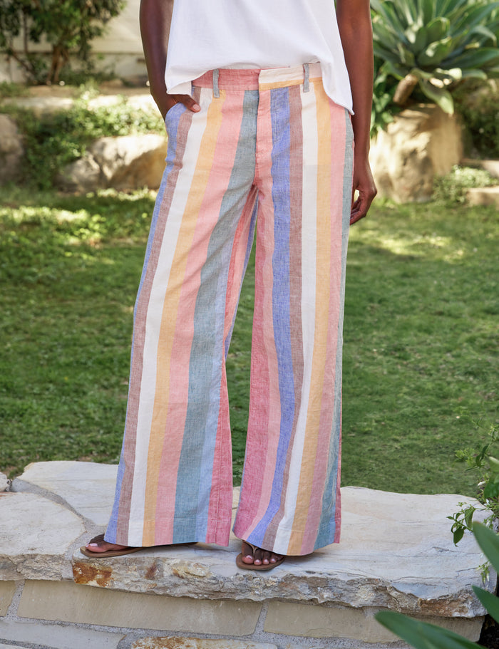 Person wearing colorful striped pants standing on a stone path with greenery in the background